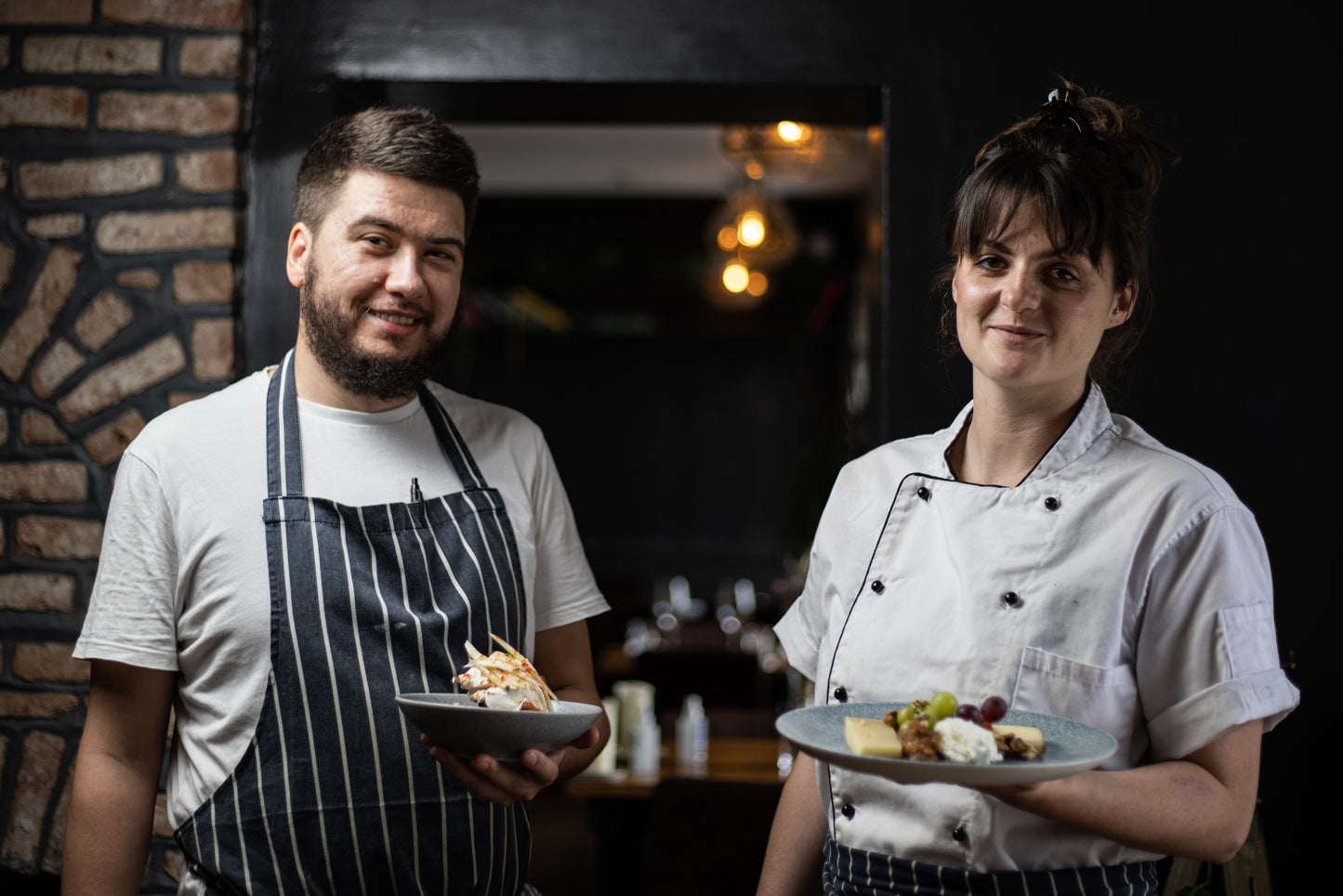 2 chefs from Ruibin restaurant, holding plates of food 